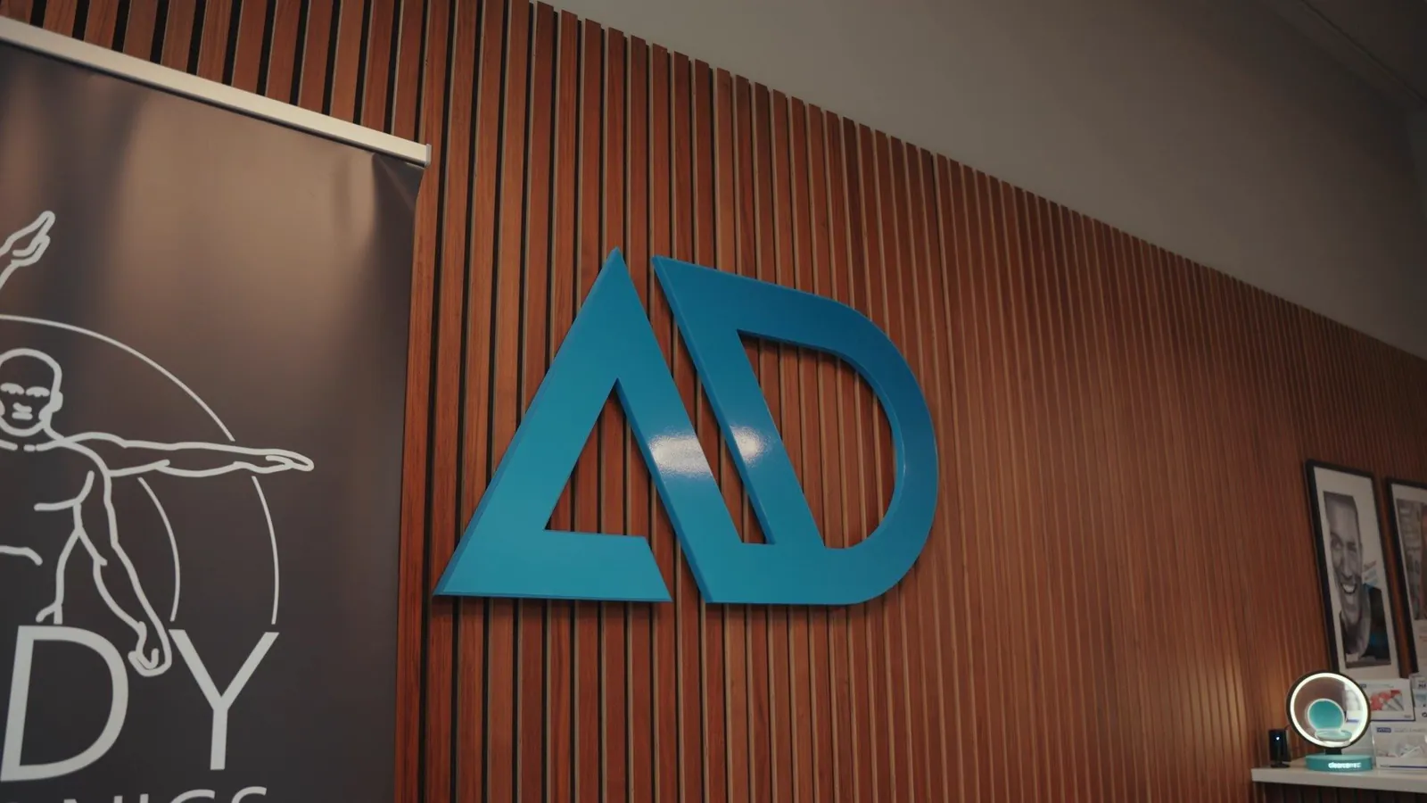 The Apex Dental logo on the wood-panelled wall at reception